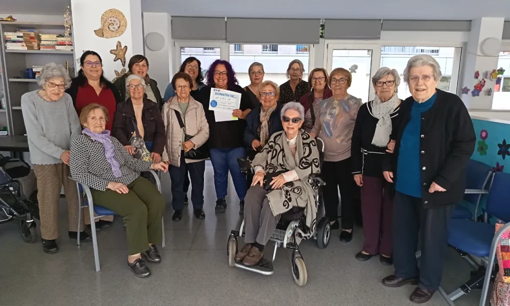 A la fotoggrafia es veuen unes 15 dones i la persona de la fundació rett amb un diploma que indica els diners recaptats